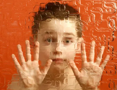 A boy with his hands up in front of an orange background.