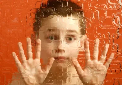 A boy with his hands up in front of an orange background.